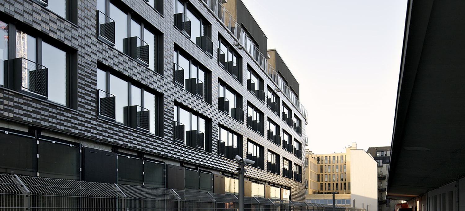 Bilde av en offentlig mørk bygning med et høyt gjerde rundt