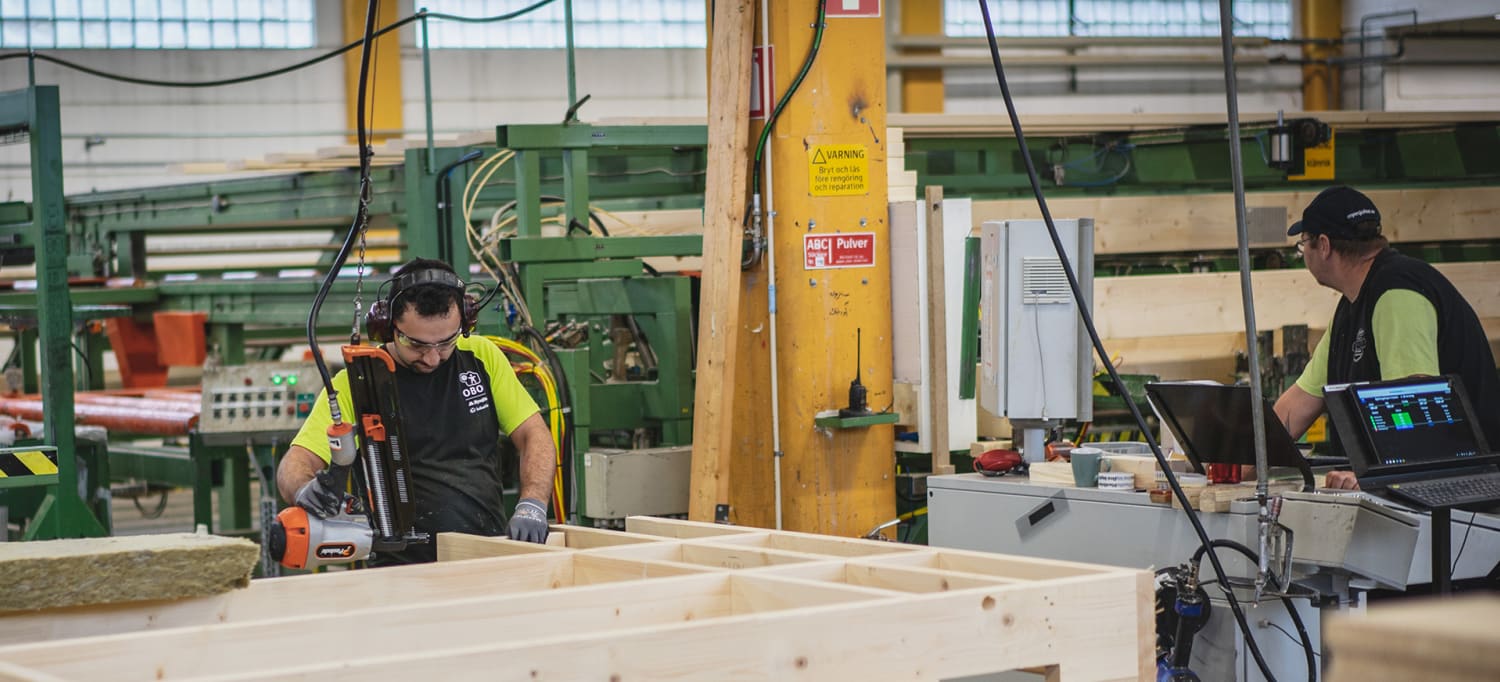 En arbetare som jobbar med trä i en obos-fabrik.
