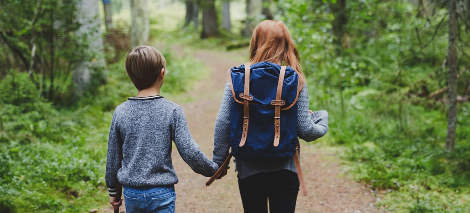 Syskon som håller hand i en skog