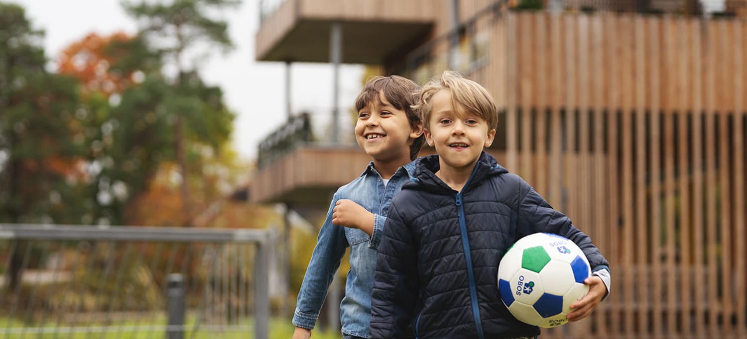 To gutter som spiller fotball i et OBOS nabolag