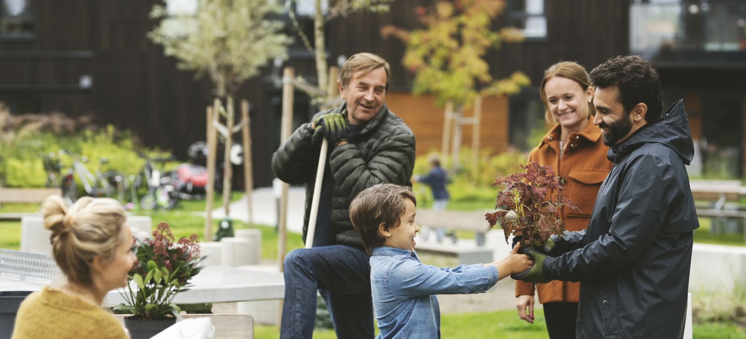 En gutt gir en plante til en mann i OBOS nabolaget