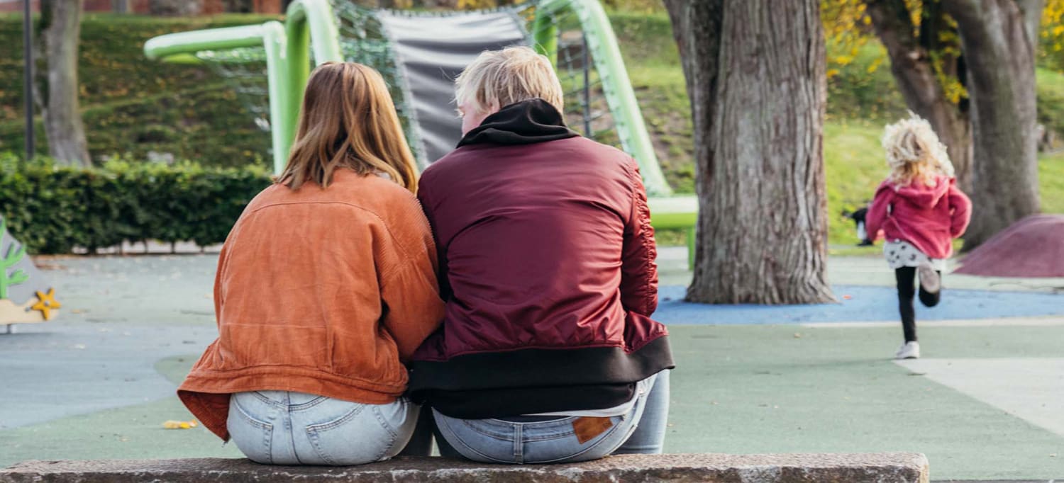 En kvinna, man och dotter i en lekpark