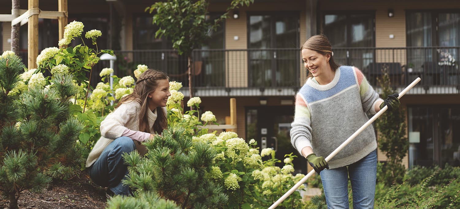 Mor og datter raker og luker i blomsterbed på Ulven.