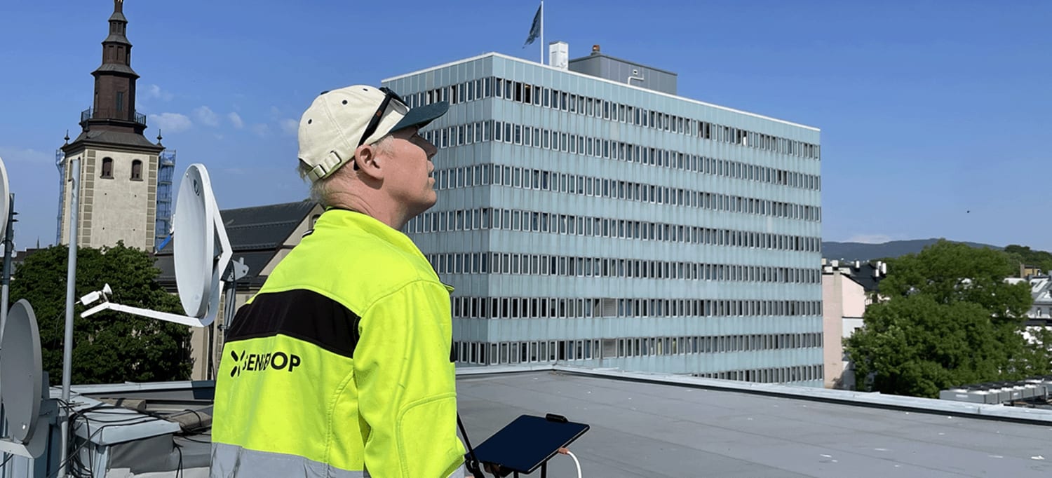 En droneoperatør står på taket til en av nabobygningene til Hammersborg Torg og scanner bygget med drone.