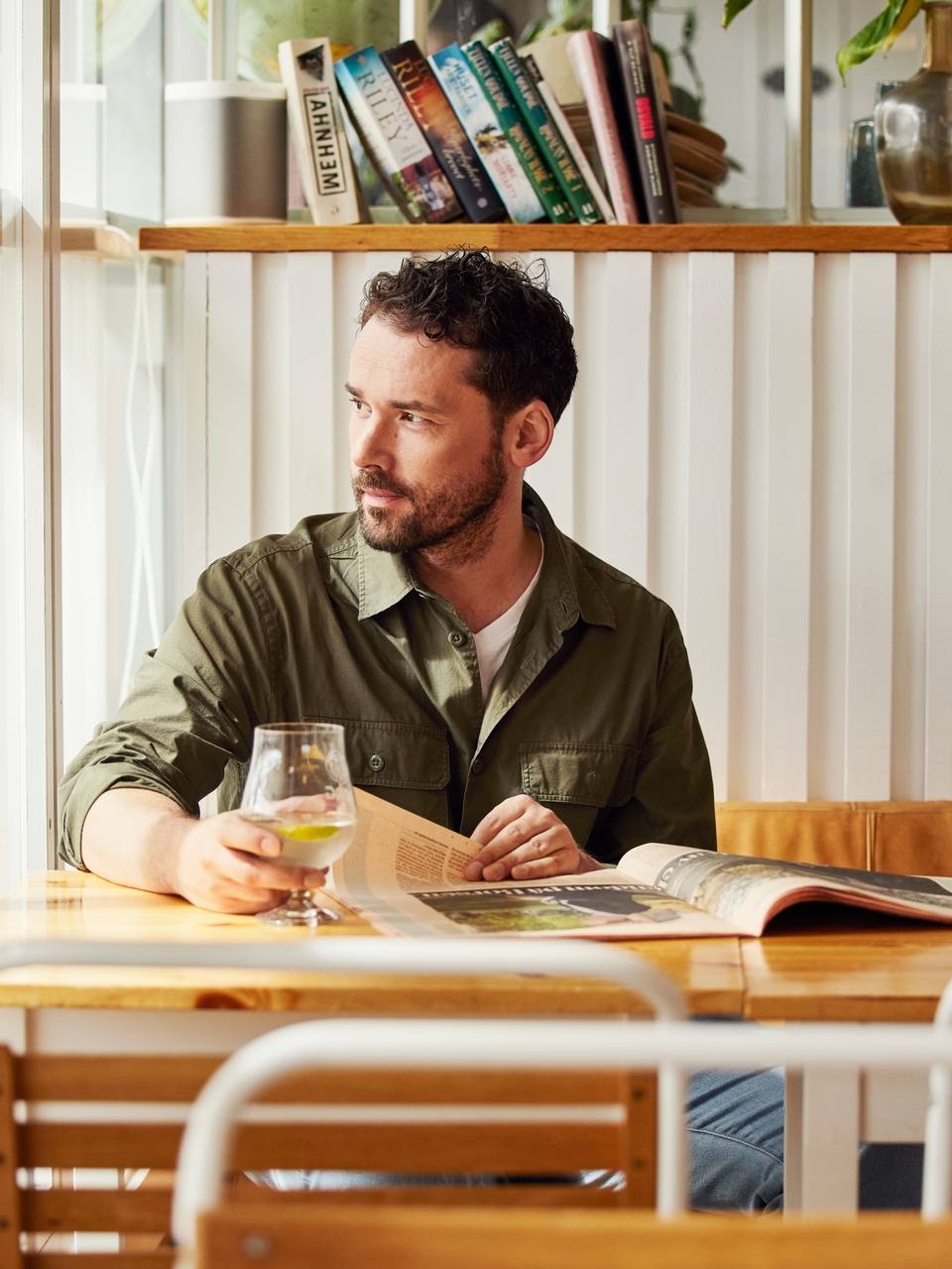 Mann som sitter på en café med et glass i hånda ved Sjøflyhavna på Fornebu