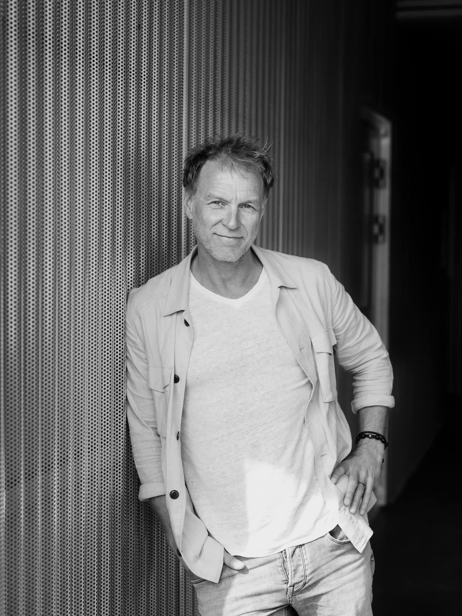 Et sort/hvitt bilde av Hans Petter, som lener seg inn mot en vegg.