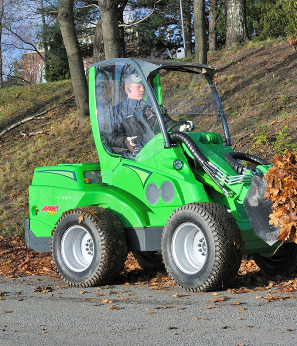 En traktor som løfter vekk løv.