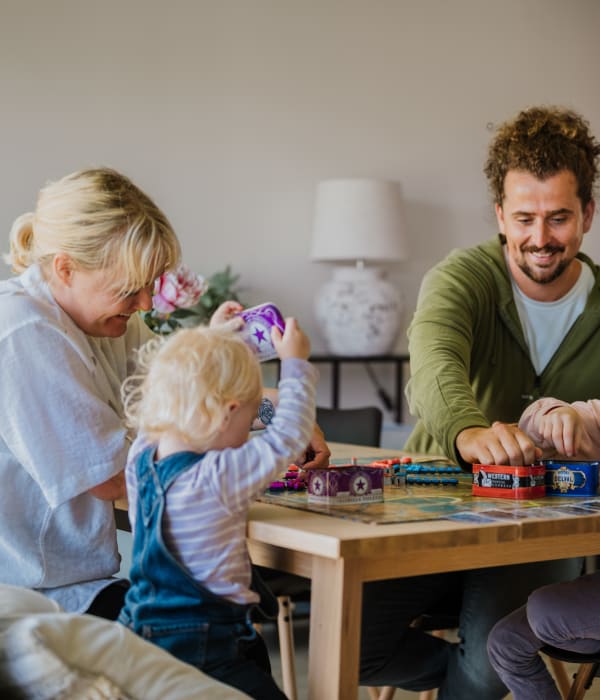 Familie spiller brettspill ved spisebordet i sin OBOS Block Watne-bolig