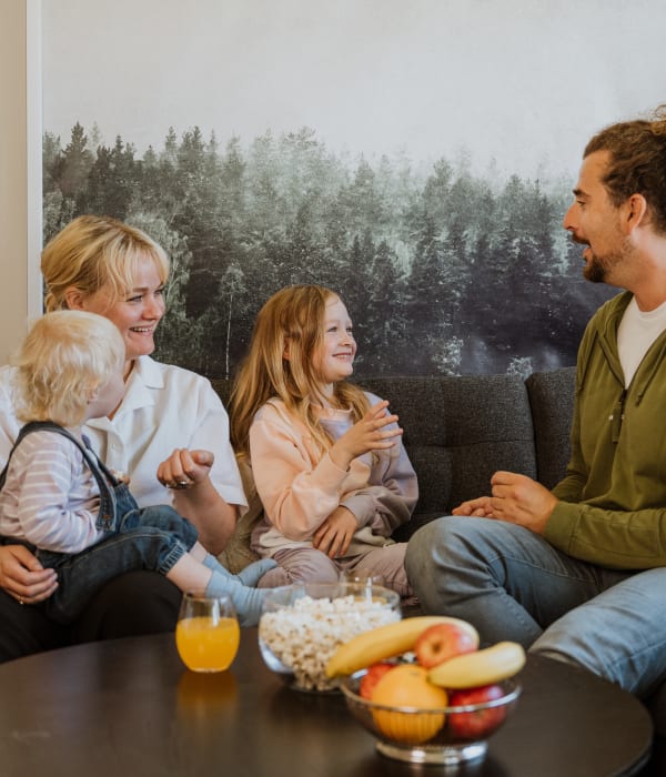 Familie på fire smiler og ler i sofa i OBOS Block Watne-bolig