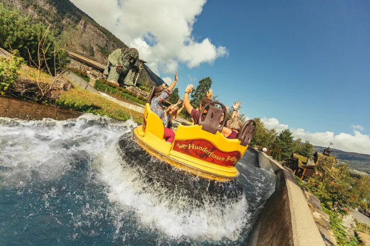 Bilde av en familie som tar en vannattraksjon på Hunderfossen med Trollet i bakgrunnen.