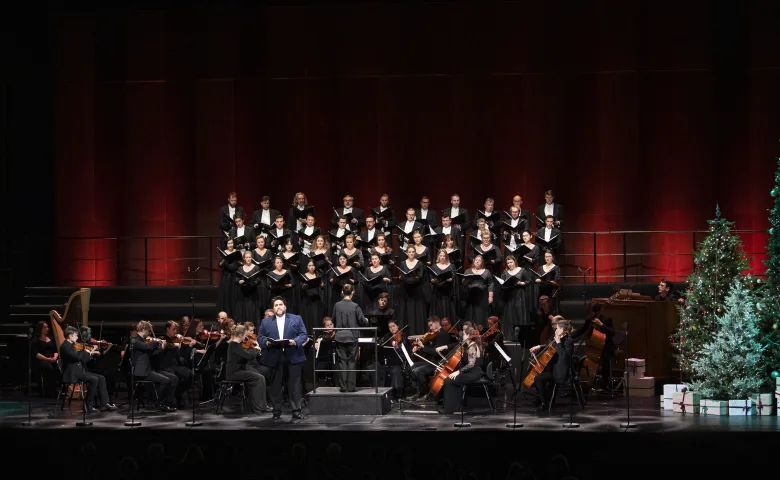 Foto av Operaens scene med fult orkester, juletre og en mannlig operasanger.
