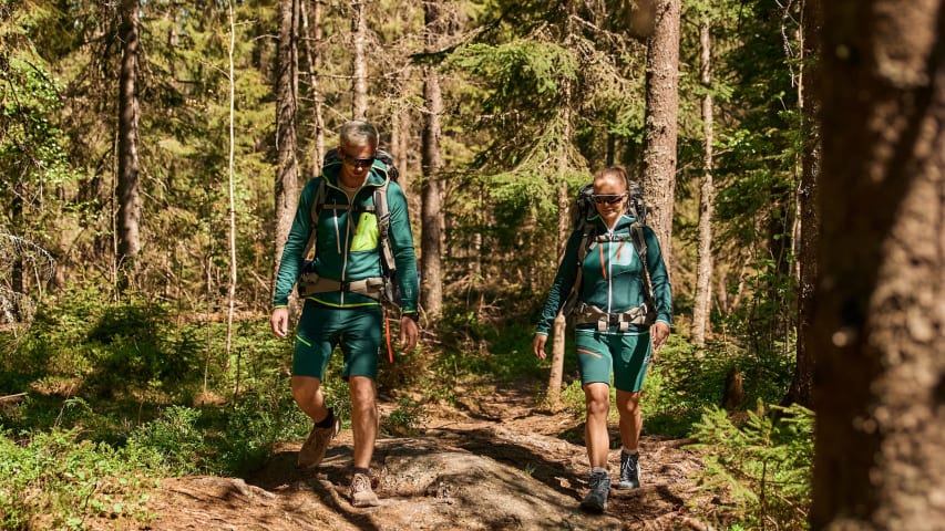 Et par går i skogen og har gode treningsklær og sekker.