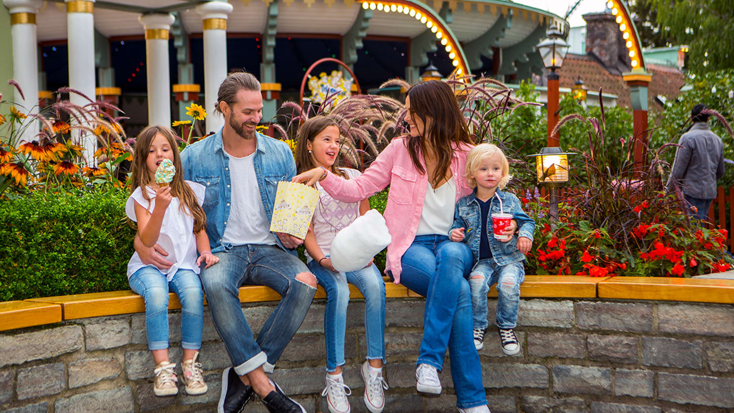 Foto av en barnefamilie på 5 som spiser sukkerspinn og popcorn på Gröna Lund.