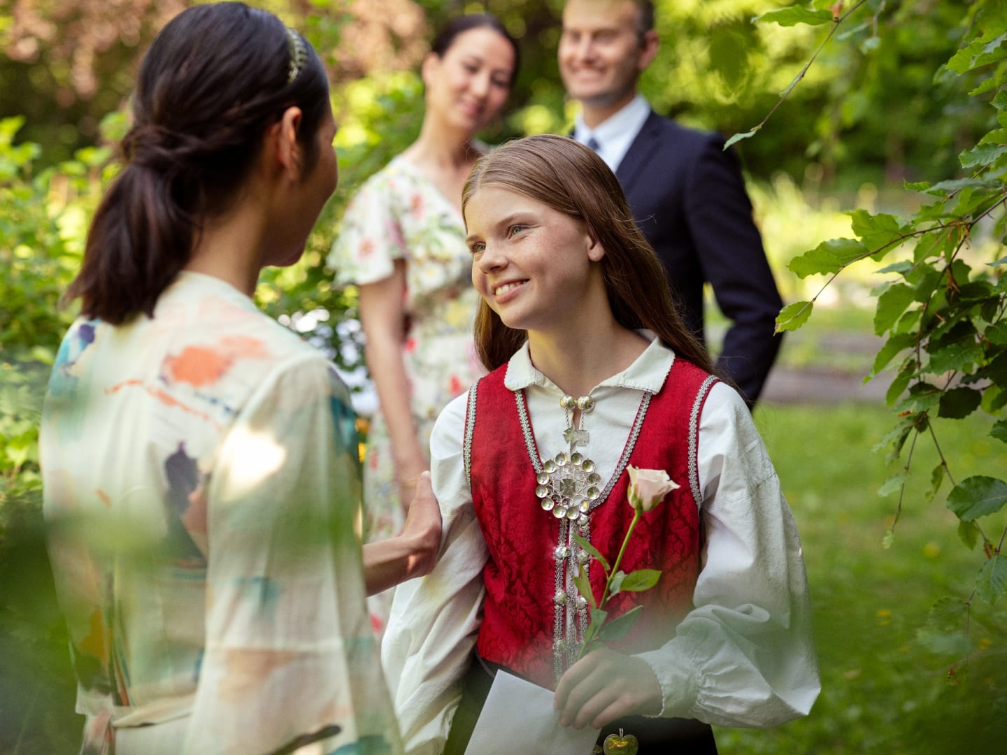 En jente feirer konfirmasjonen og har på seg bunad. Hun takker en annen dame for gaven.