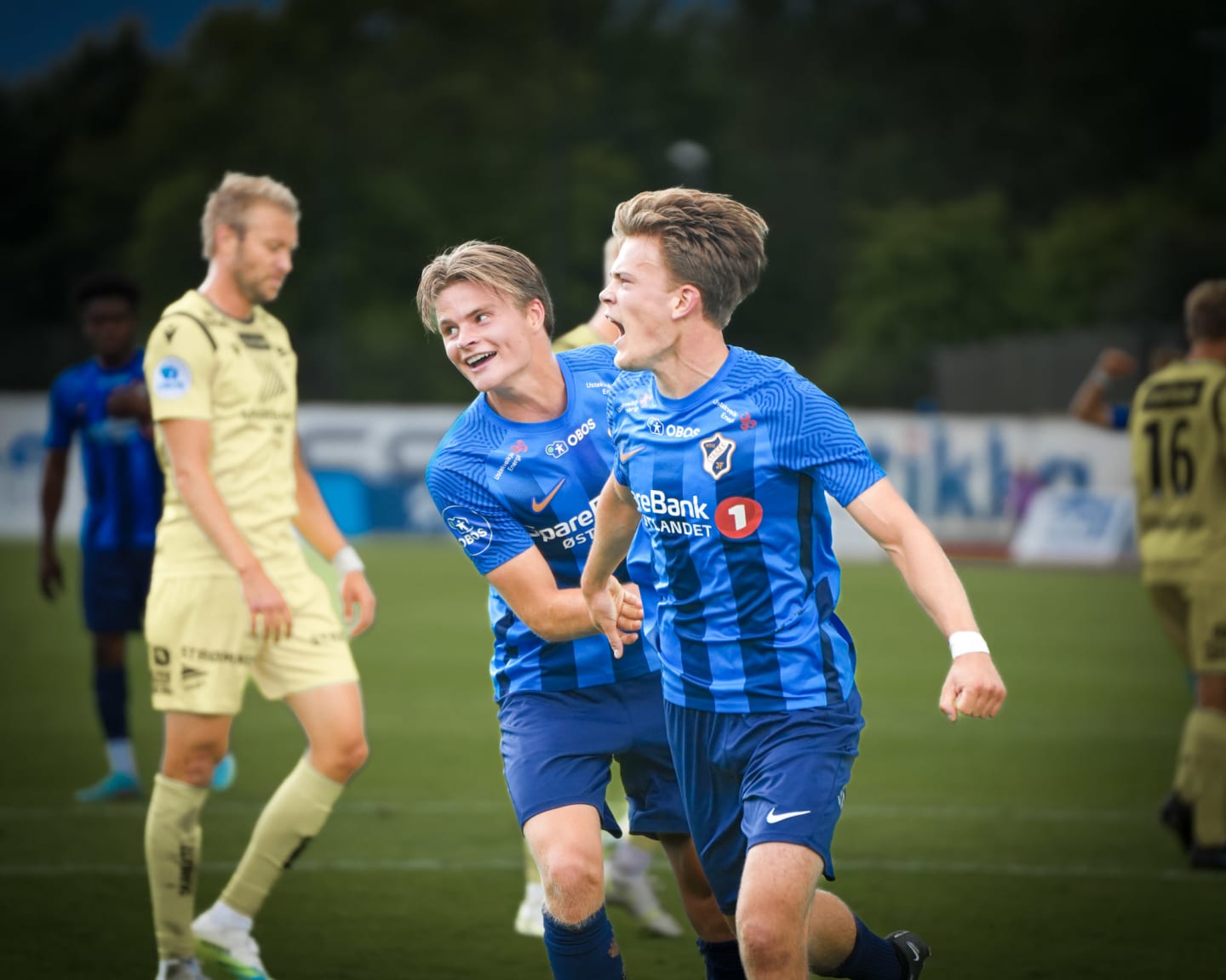 En gruppe jenter i stabæk fotballdrakt som løper på rekke ut på fotballbanen mens supportere tar hight five med dem.