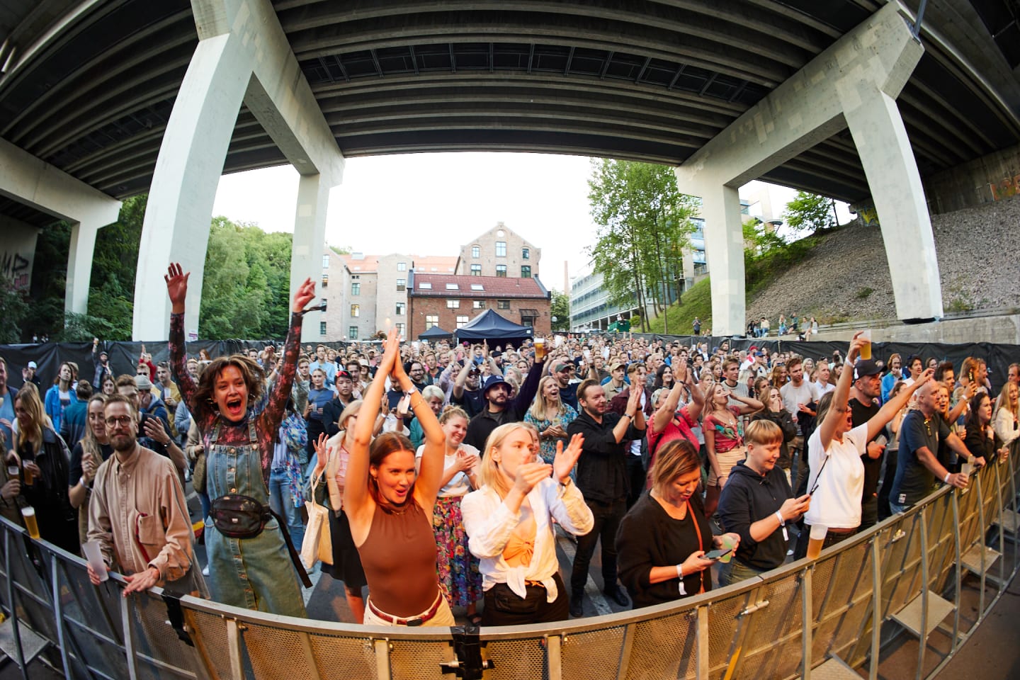 Foto av publikum på festivalen Langs Akerselva som jubler mot scenen i sommervarmen.