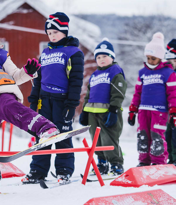 Glade barn på ski som står i kø for å gjennomføre øvelse.
