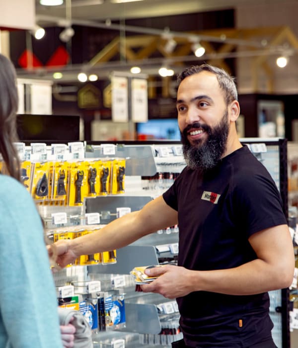 En mannlig ansatt i monter hjelper en kunde i butikken