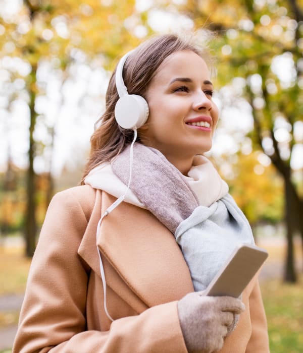 Jente lytter tii podcast ute på tur i høstlige omgivelser.