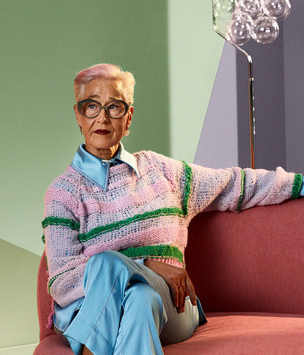 Dame sitter på sofa i et fargerikt rom med maling fra Flügger.