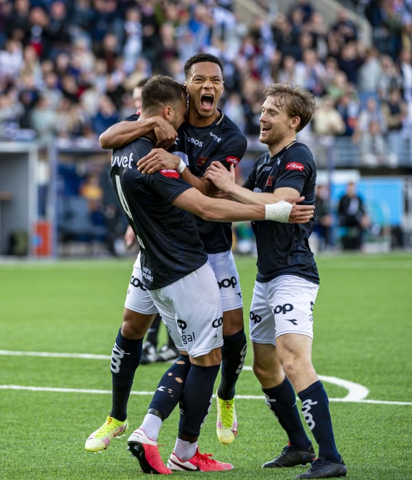 Tre fotballspillere fra Viking som klemmer og feirer sammen på den grønne fotballbanen