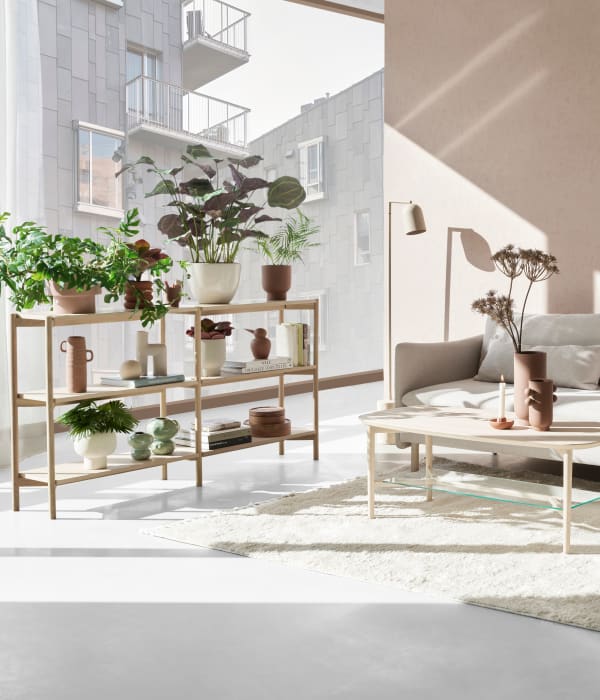Bilde av en lys stue med en beige sofa og et stort vindu på venstre side som slipper sollys inn i rommet