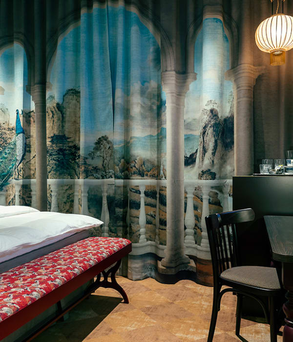 Foto av et kunsnerisk hotellrom hos Grand Curiosa Hotel med seng, skrivebord, gardiner og en TV med hotellets logo på skjermen
