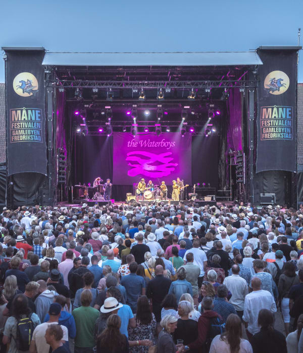 Foto av Månefestivalen med en lilla lys på scenen og publikum som står og hører på konserten.