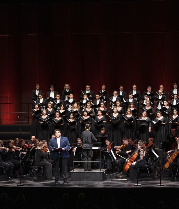 Foto av scenen på Operaen med fullt orkester, juletre og en mannlig operasanger.
