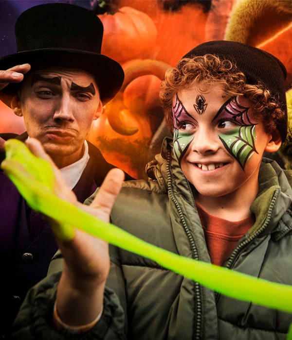 Halloween på Liseberg. I bildet ser vi en unge med ansiktsmaling og i bakgrunn er det en magiker og en kaninmaskot.