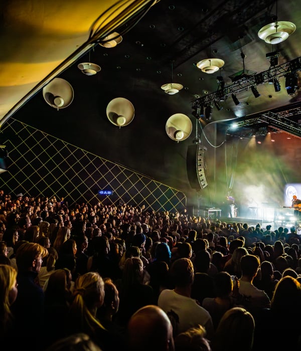 Konsert der du ser scenen og publikum. Scenelysene farger bildet.