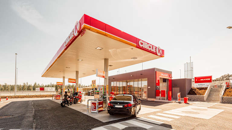 Bilde av en Circle K-stasjon langs veien. Det er både motorsykler og en bil utenfor.