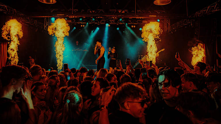 En artist står på scenen og synger under en konsert.
