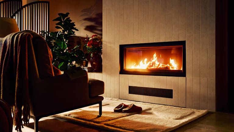 En stol med et pledd over står foran en vedpeis