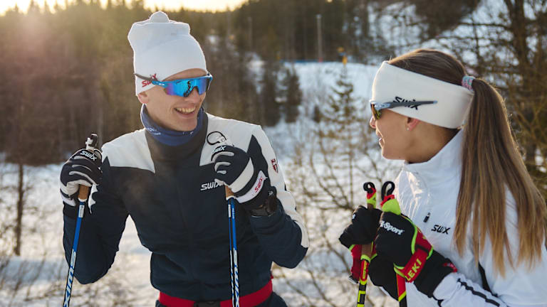 To personer står på ski ute. De har på seg Swix-klær og utstyr.