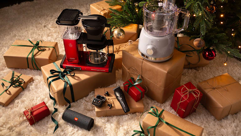 Illustrasjonsbilde av ulike produkter som både er pakket inn og ikke. De ligger under et juletre. Du ser blant annet en Moccamaster.