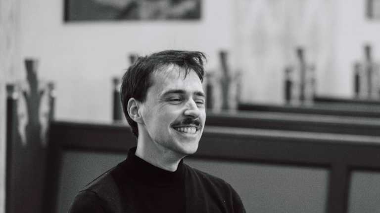 En pianist spiller piano og smiler bredt.