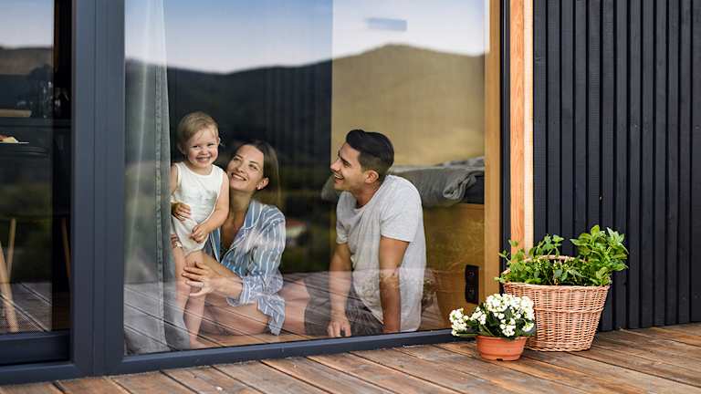 En dame og en gutt putter ved i en peis. Du ser lyset fra flammene. De smiler.