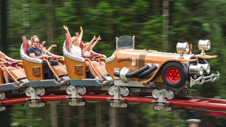 Flere mennesker sitter i en karusell. De har armene opp.