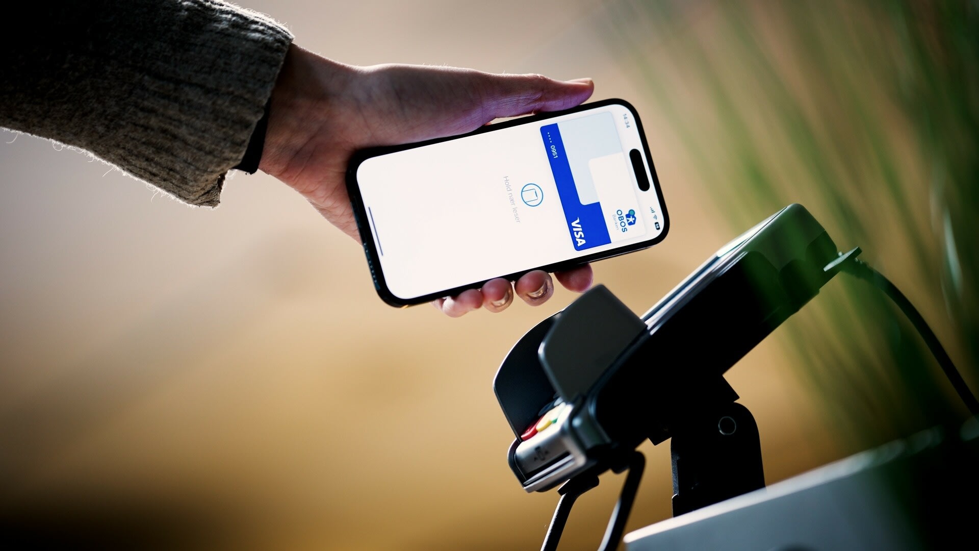 En hånd som bruker mobilen sin til å betale med Apple Pay