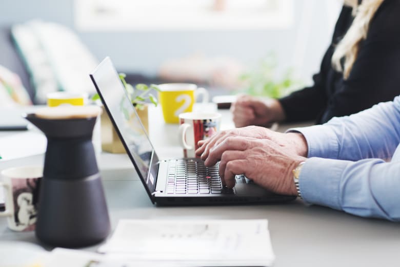 Person jobber på laptop med kaffe ved siden av seg