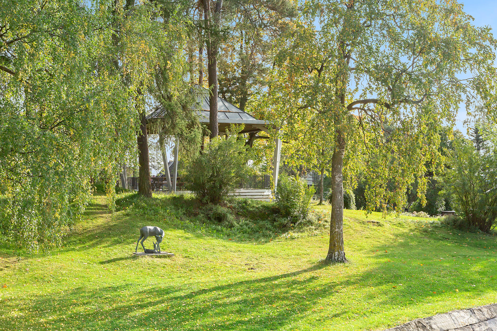 Hamar Park på sommeren med grønt gress og lysthus.