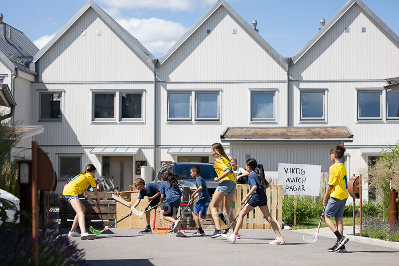 Barn spelar innebandy bland husen