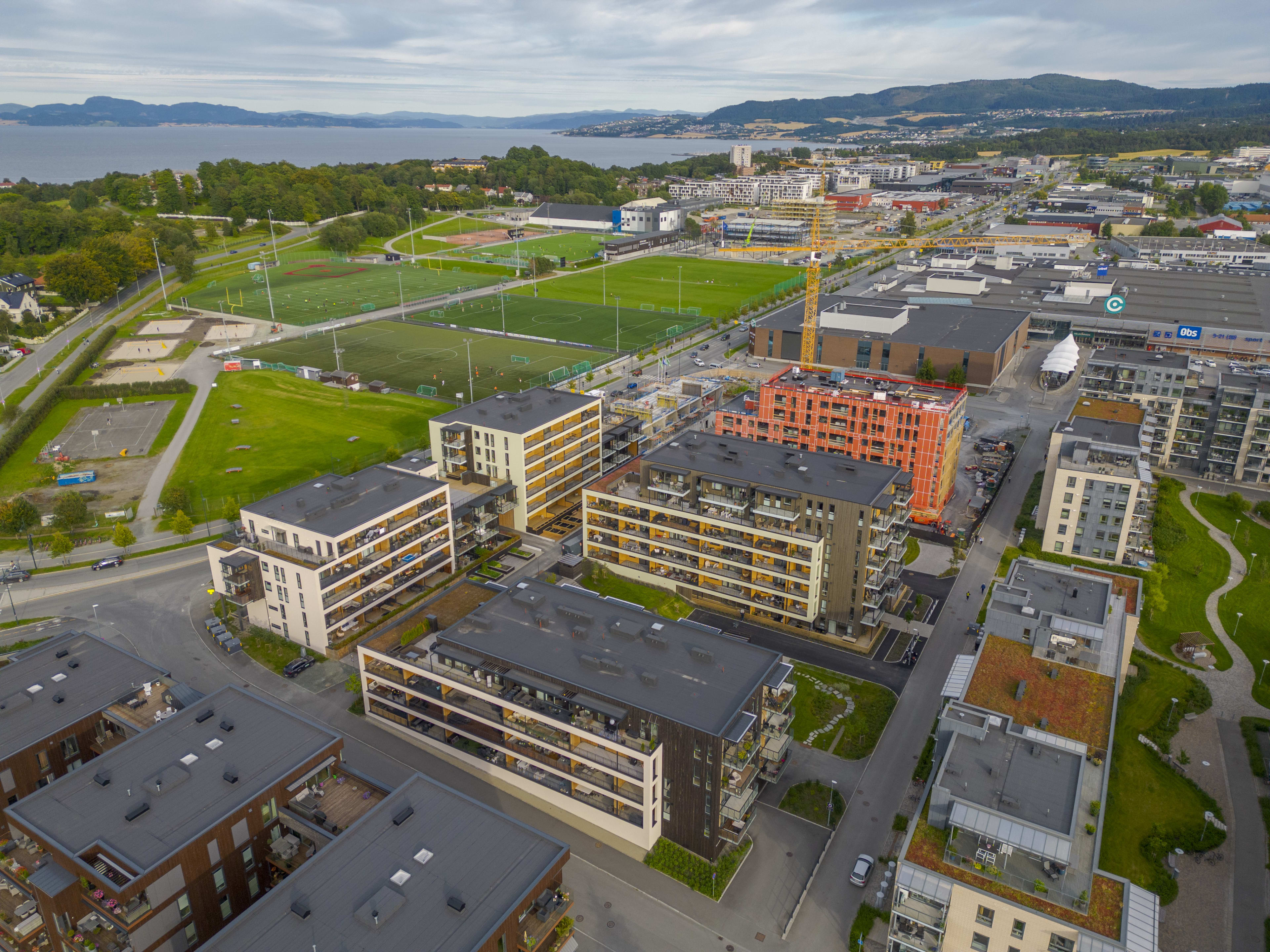 Foto av alle byggene i Ladebyhagen med fotballbane i bakgrunnen.