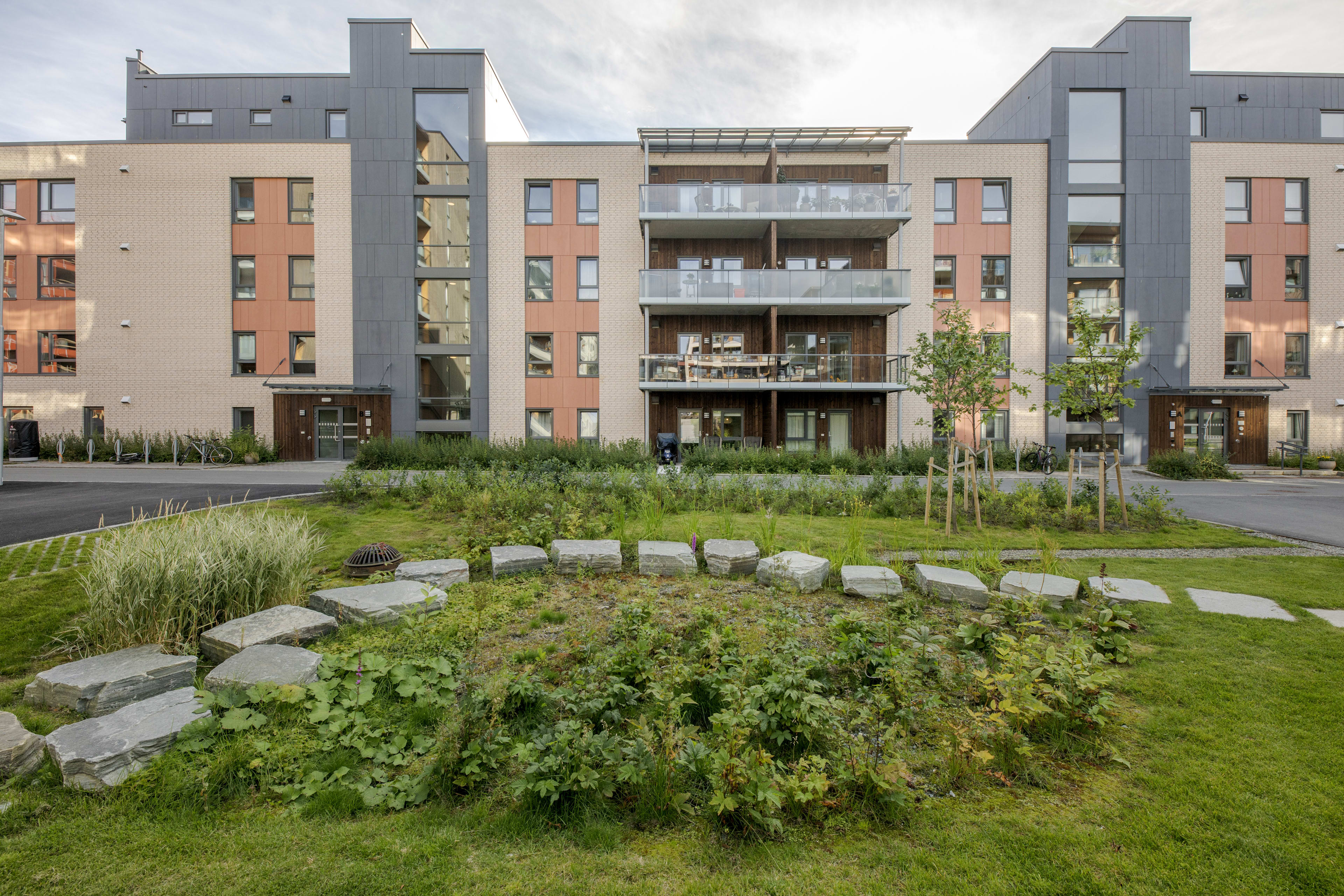 Foto av fasaden til byggene i Ladebyhagen med grønt område foran.
