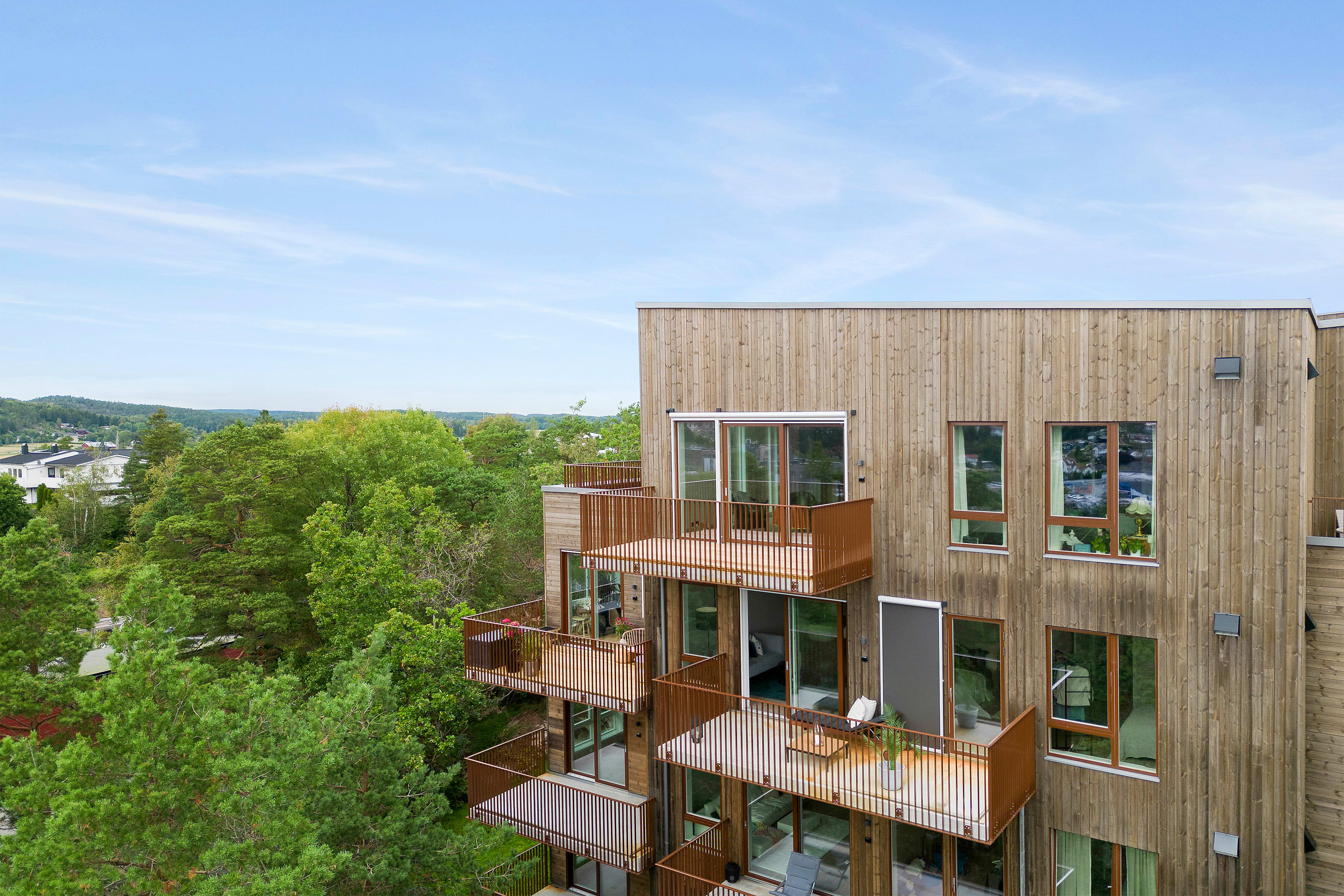 Foto av fasaden til boligprosjektet Haraldåsen med store balkonger og grønne trær.