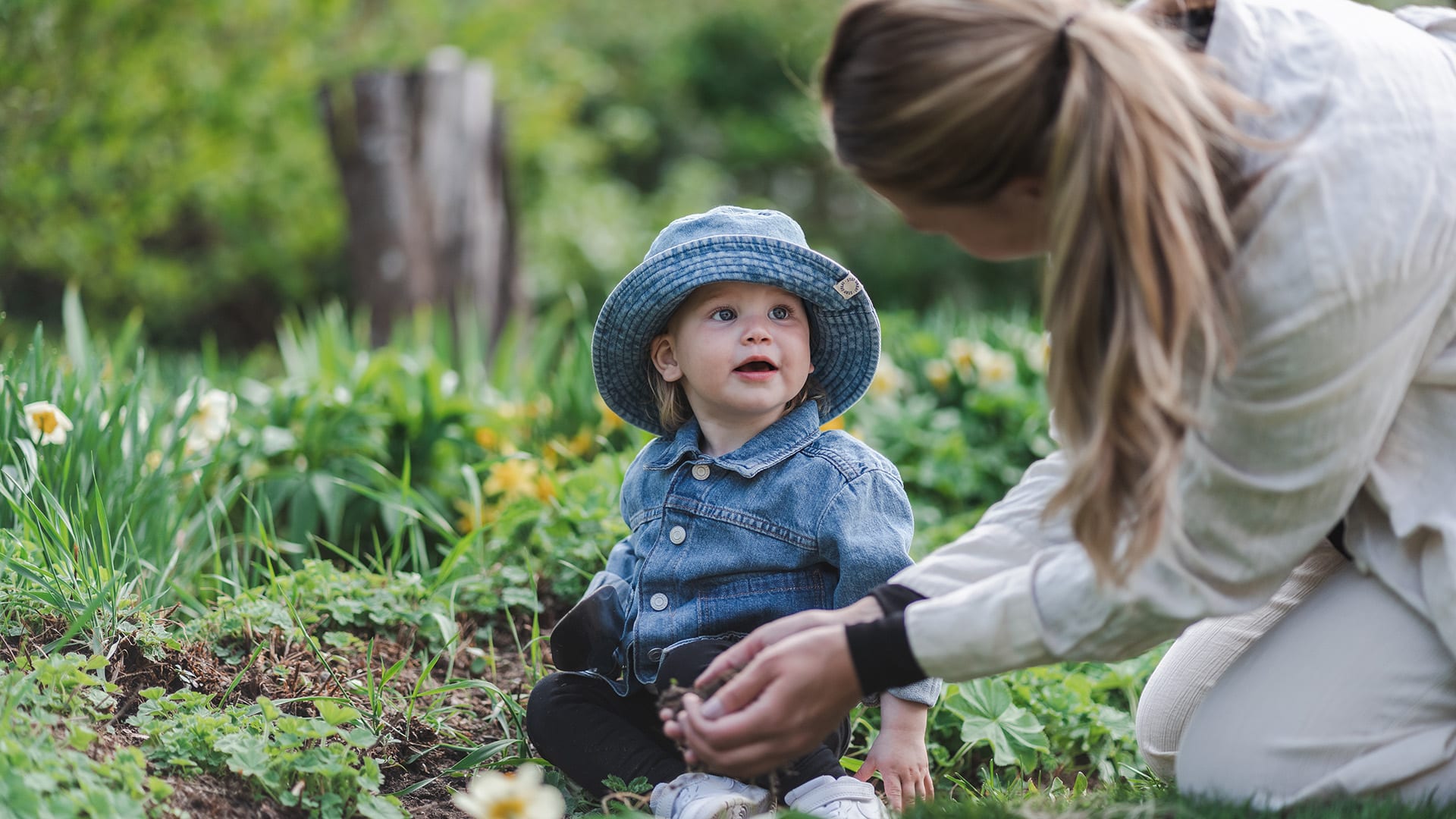 Foto på ett barn och en mamma som sitter på marken och planterar i jorden