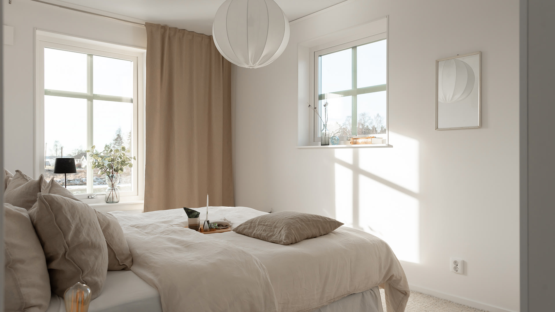Bild: Sovrum i beige med dubbelsäng och fint ljusinsläpp från fönster.