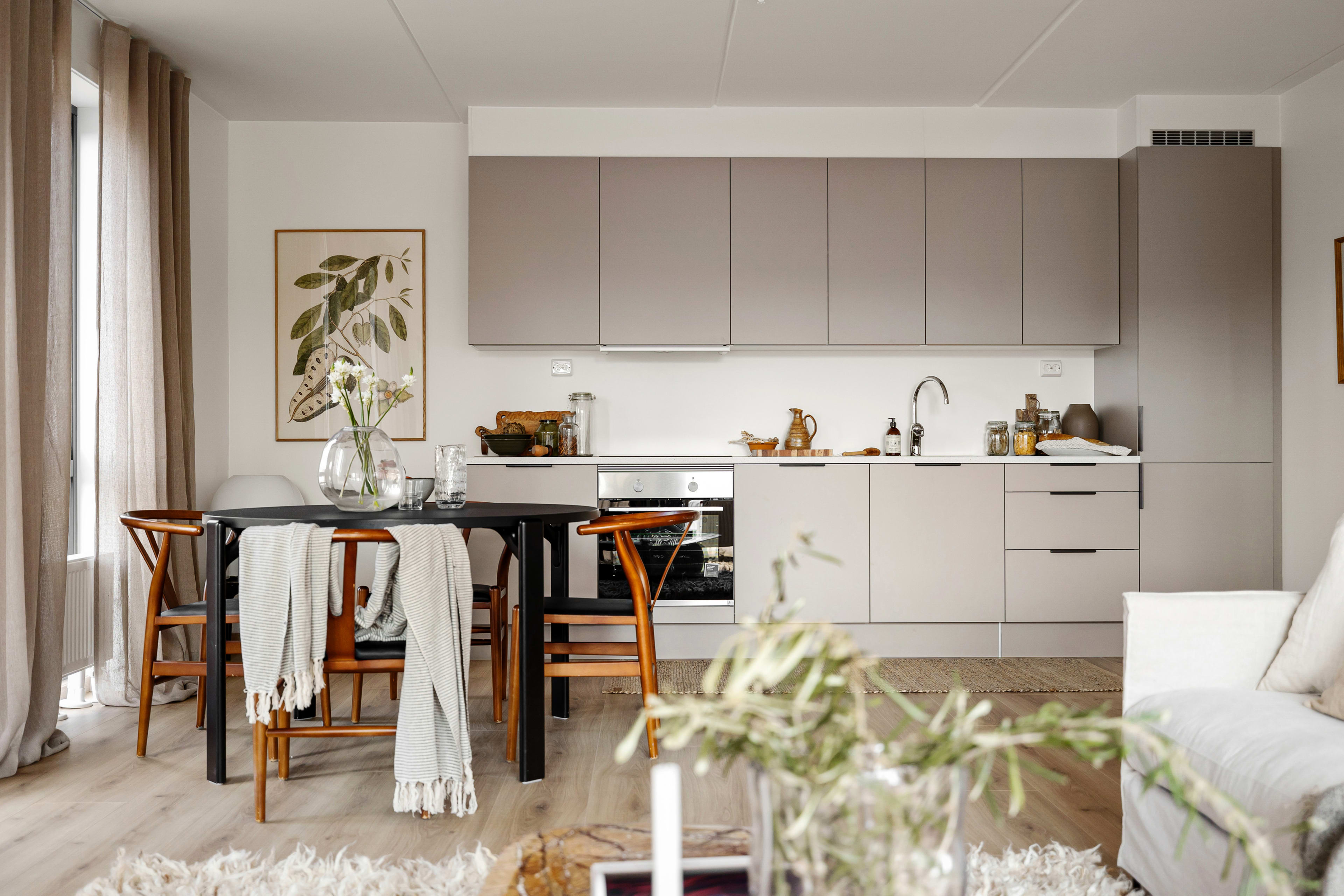 Bilde av et beige kjøkken, spisestue og en lys sofa i en leilighet i Ulvenkroken