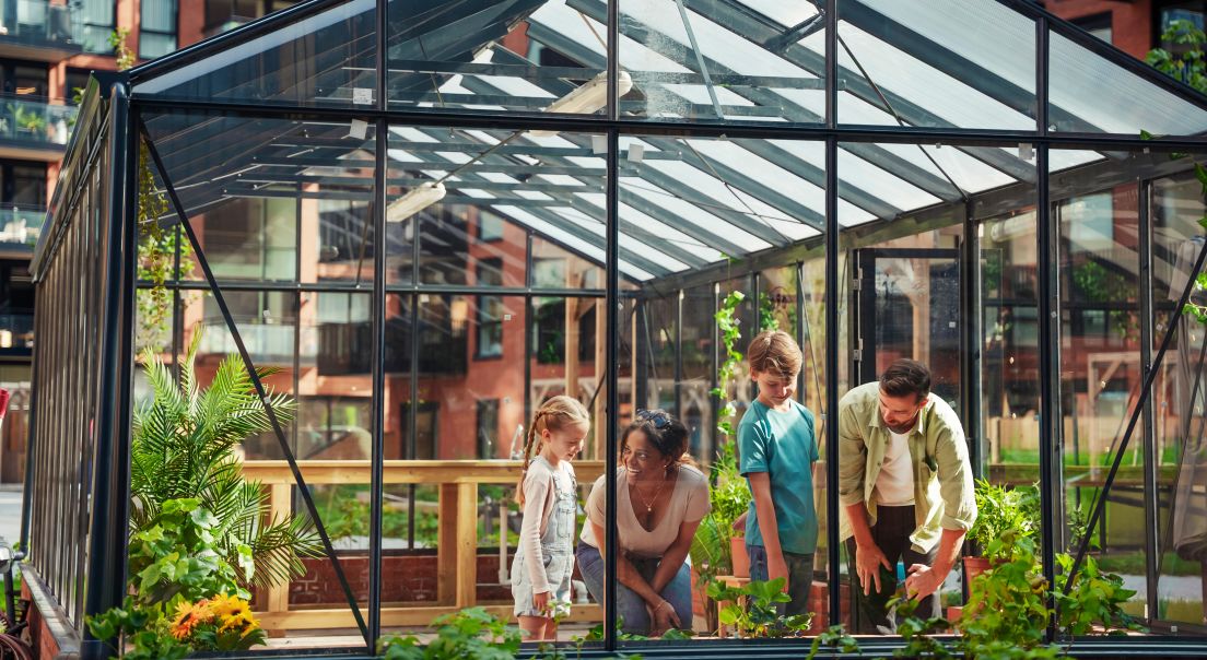 Familie som holder på i et drivhus i Løren botaniske